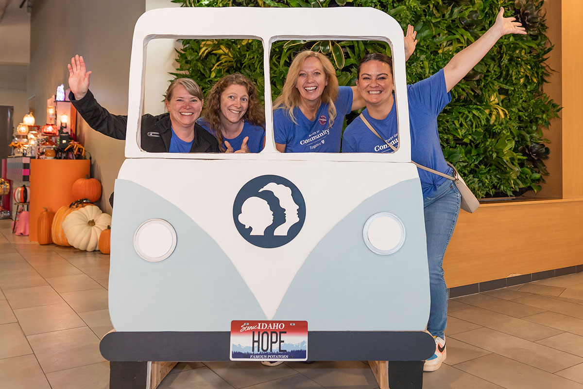 group of happy people standing behind a large cutout of a hippie van for photo ops