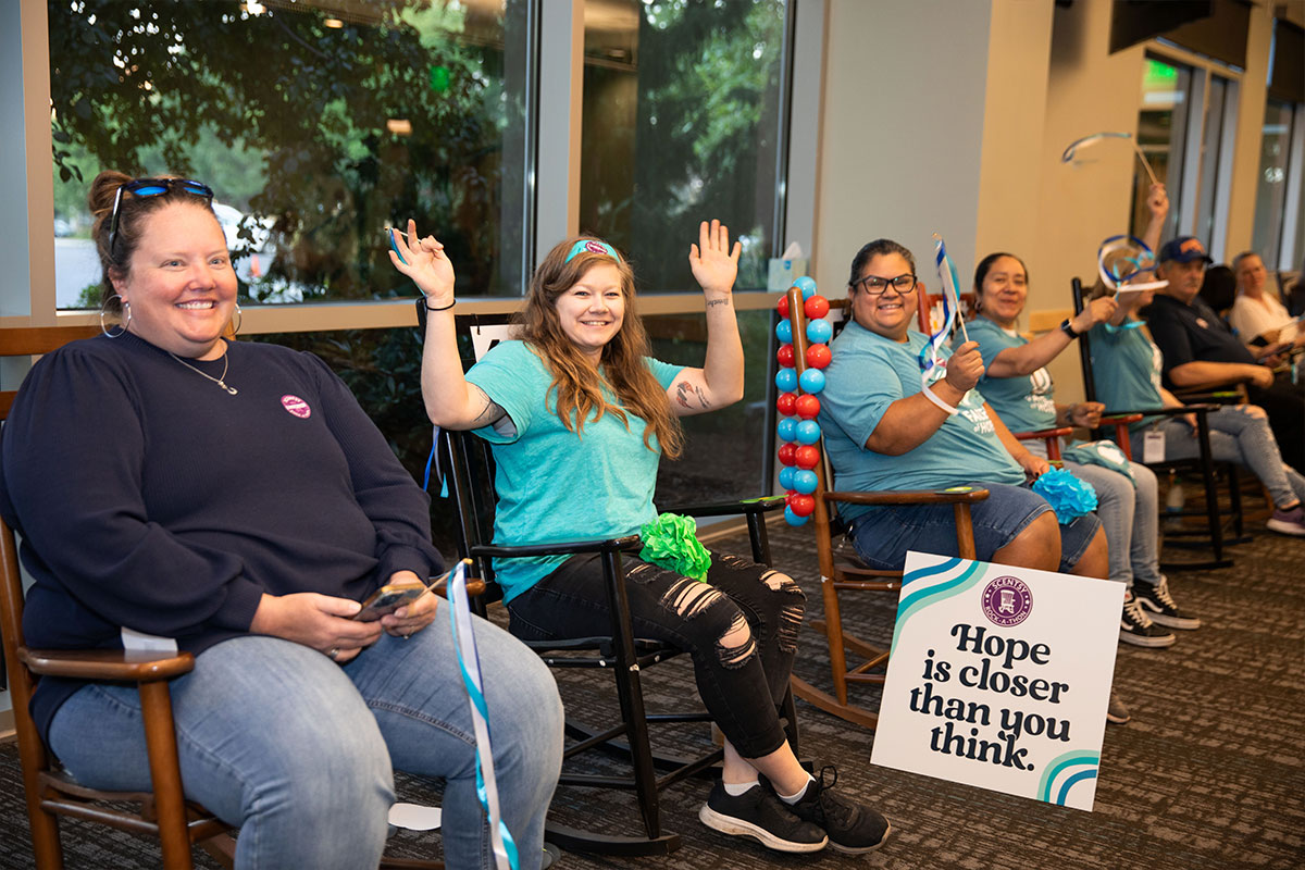 group of happy people rocking in rocking chairs and waving