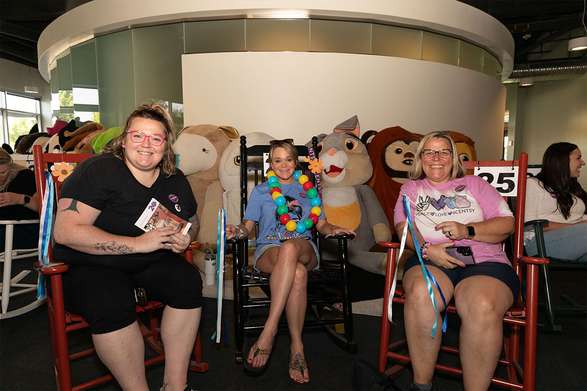 three happy women rocking in rocking chairs with oversized stuffed animals in the background